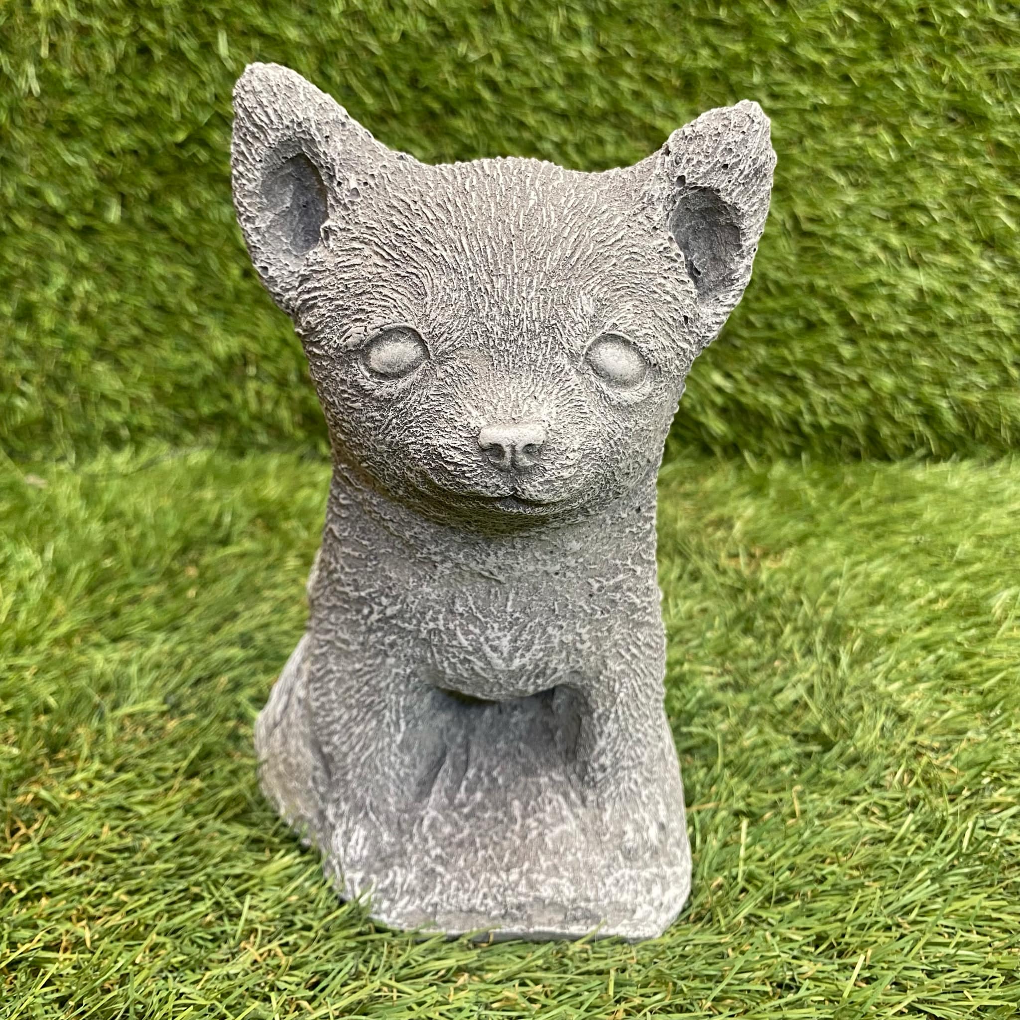 Stone statue of a Chihuahua on grass