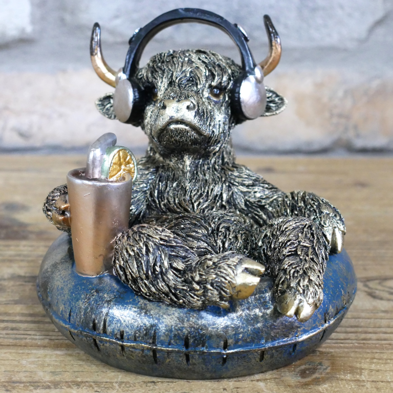 Statue of a bull with headphones and a drink on a wooden surface