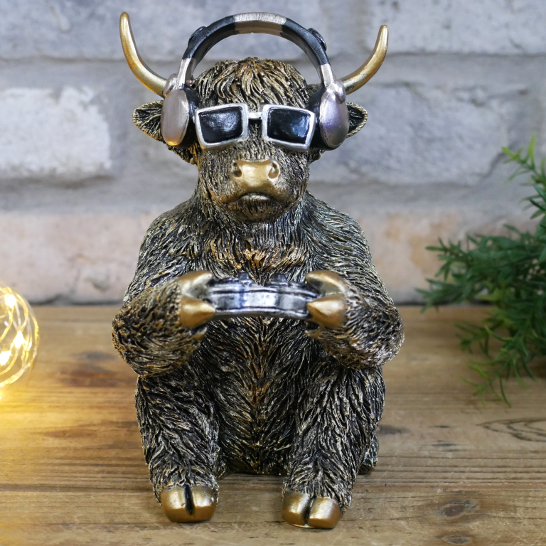 Statue of a bull wearing headphones and sunglasses on a wooden surface with a light bulb and plant in the background.